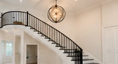 A curved staircase with a black metal railing.