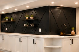 A geometric dark feature wall above custom white cabinetry.